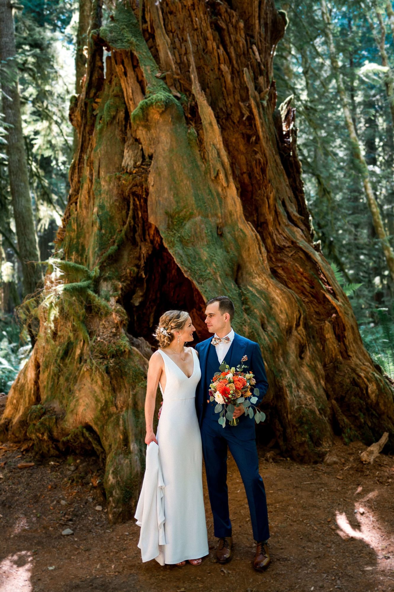 bride with Groom holding bridal bouquet in front of ancient tree