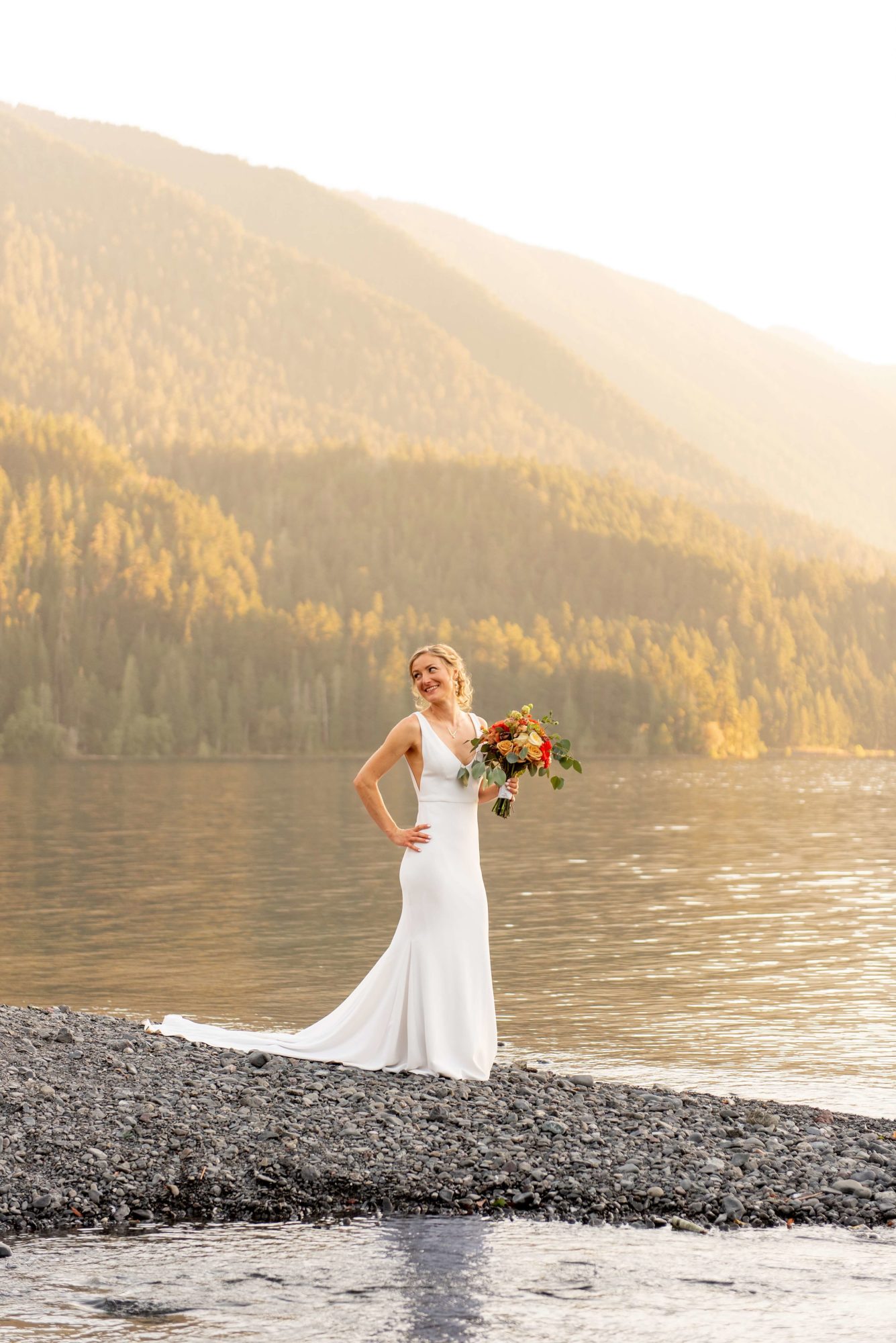 bride holding flowers by lake