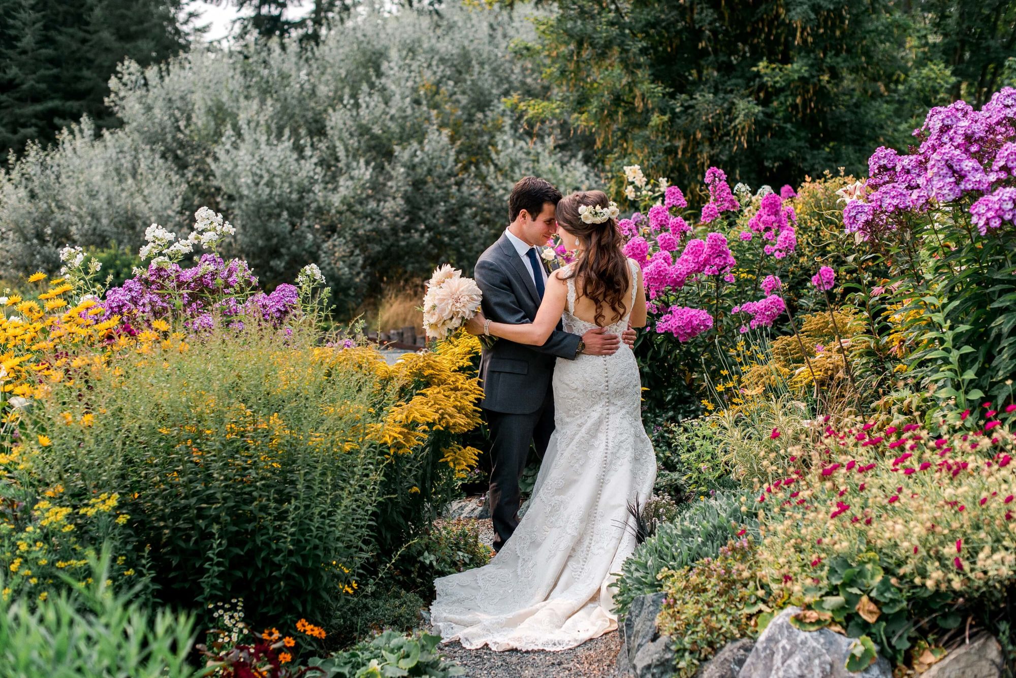 Bride and groom dancing in the flower garden surrounded by flowers at a fireseed catering wedding