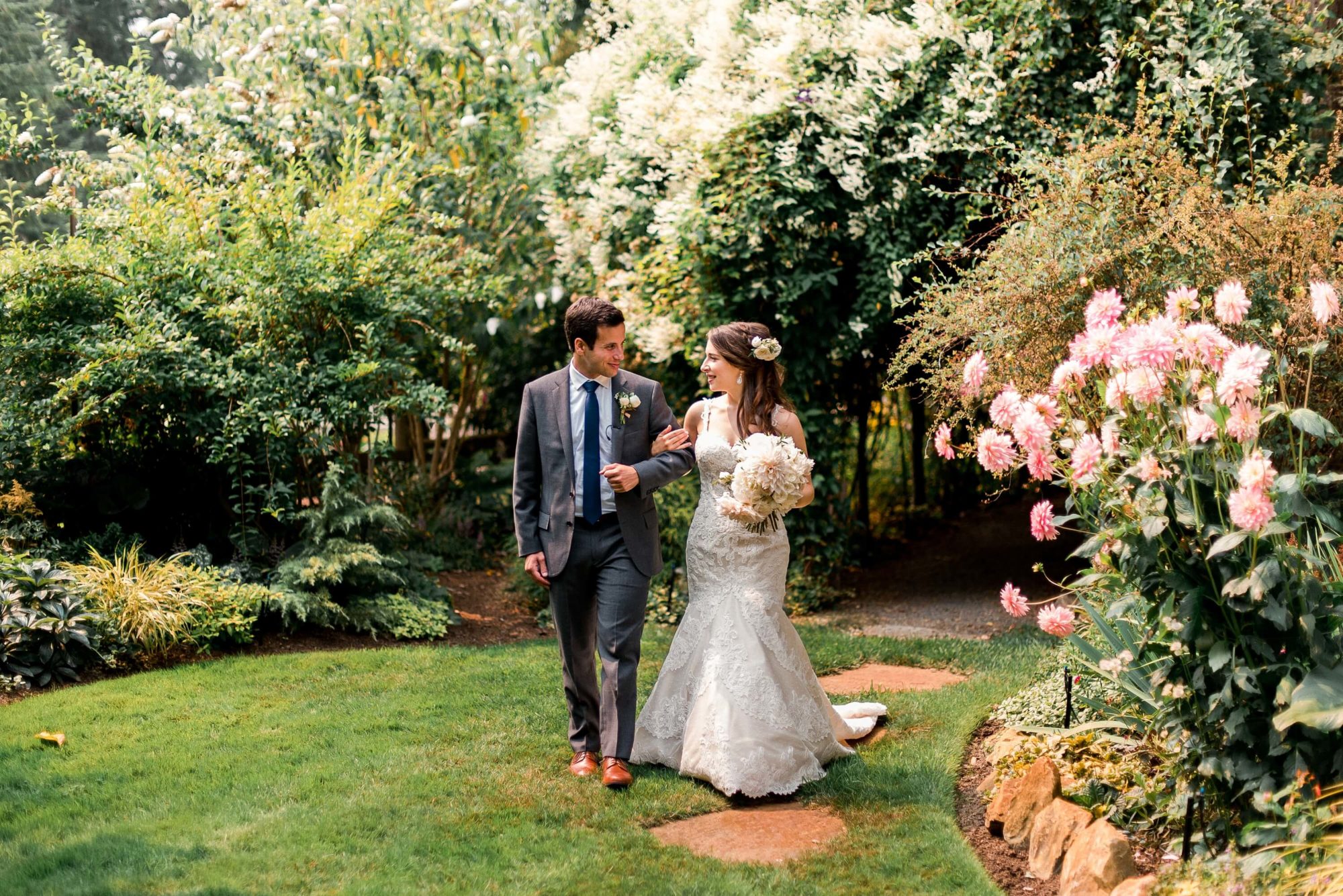 bride and groom walking through the garden arm in arm looking at each other at Fireseed catering wedding venue