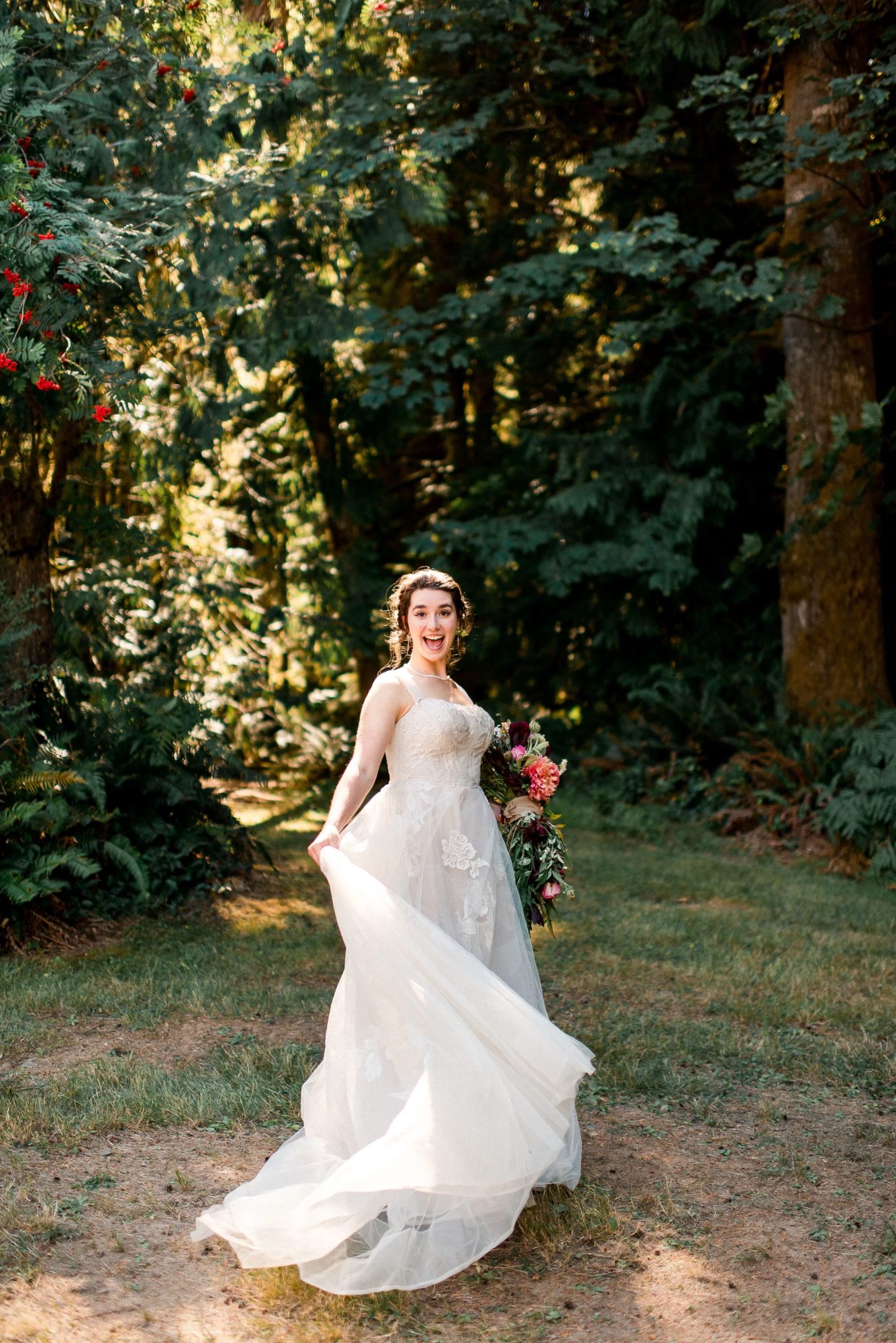 Bride playing with her dress and flowers in a forest path at The Lodge at St. Edwards