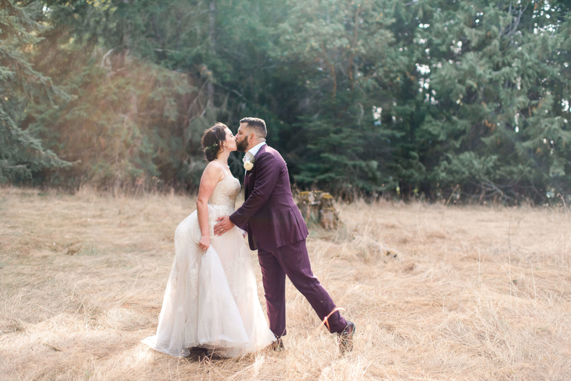 bride and groom kiss in a golden grass field
