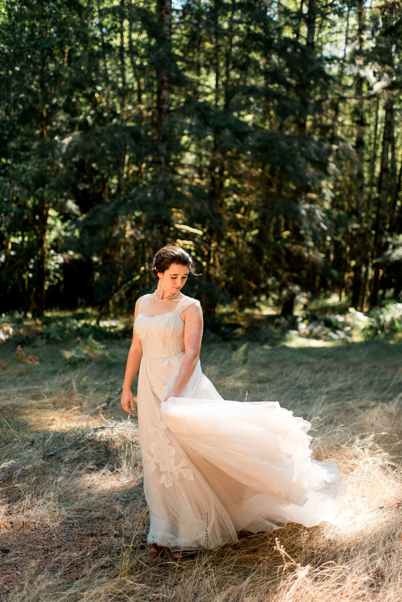 bride walks with her dress in the windy forest at The Lodge at St. Edwards