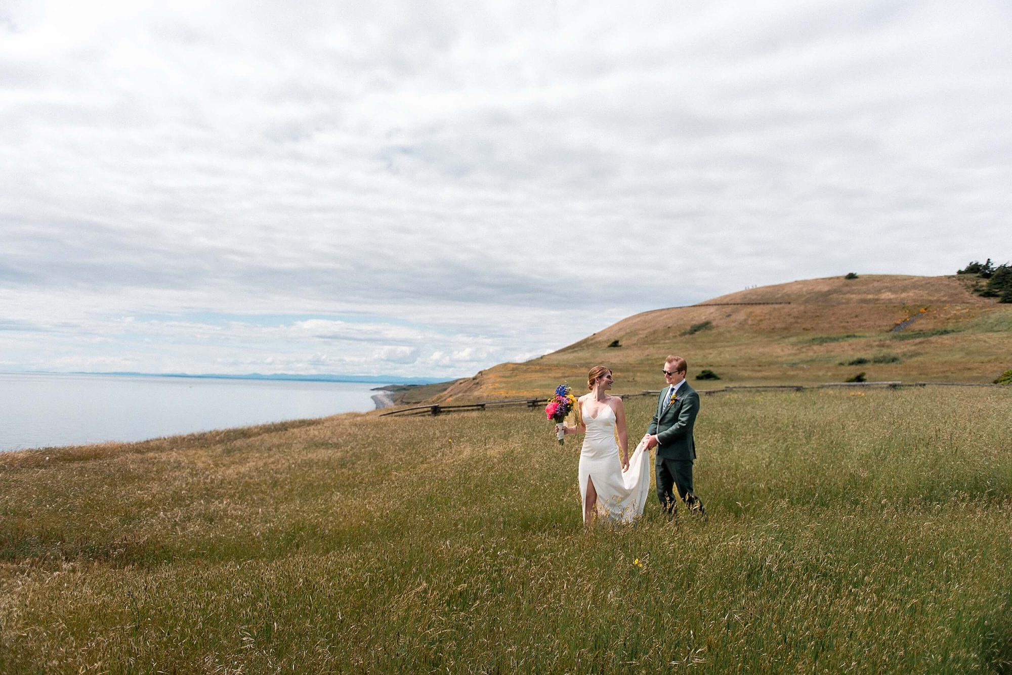 bride and groom walking through a field at their San Juan Island Wedding