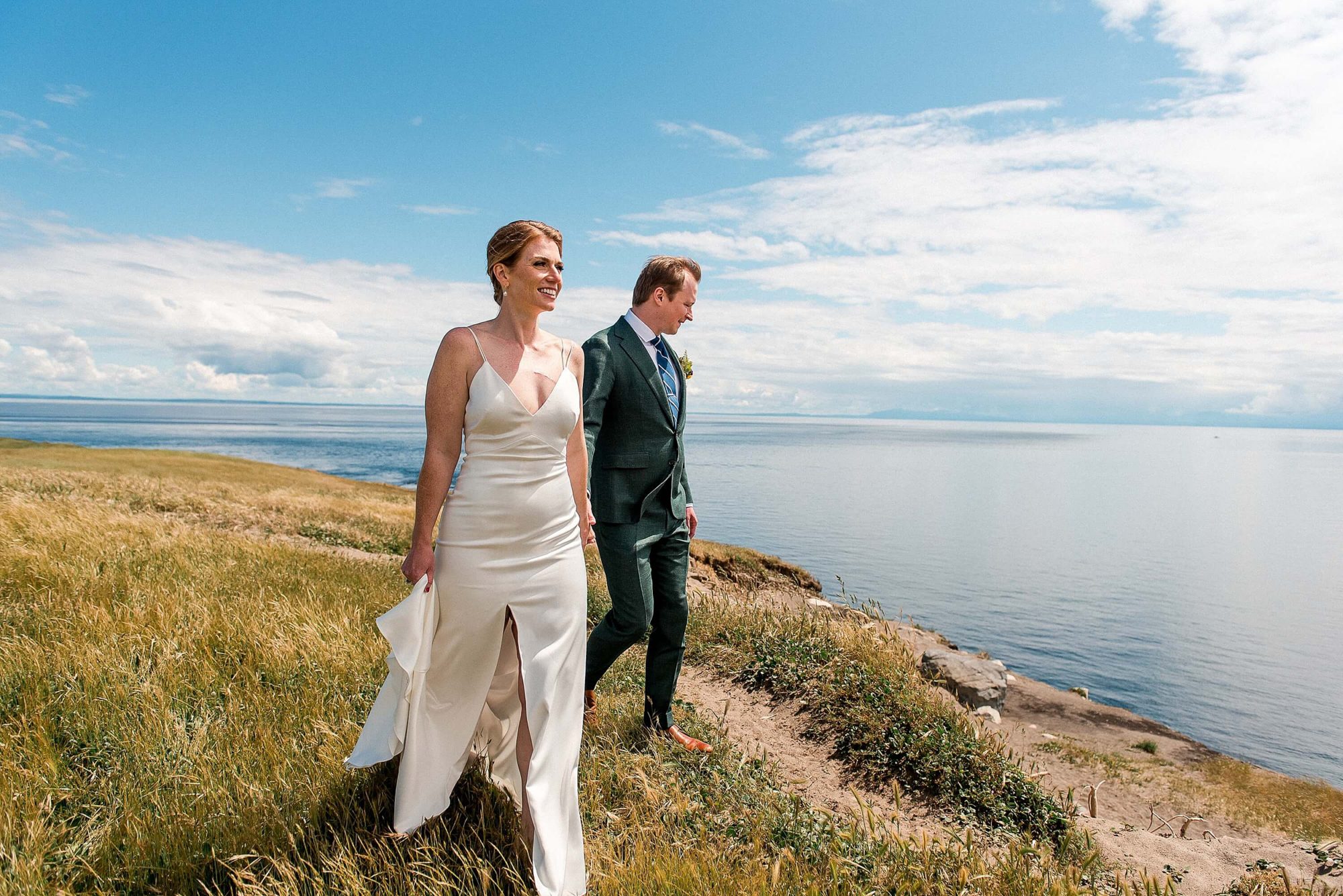 bride and groom walking along a cliffside at their San Juan Island Wedding