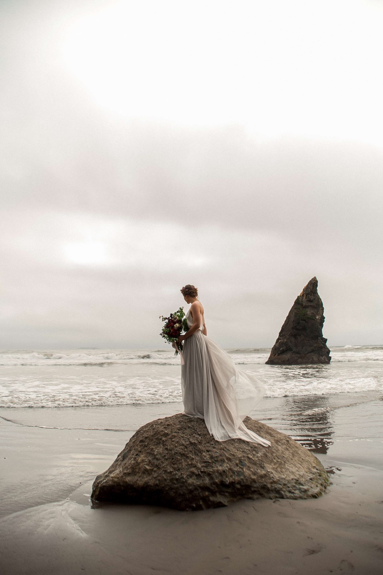bride standing on a rock on the beach at their Seabrook wedding