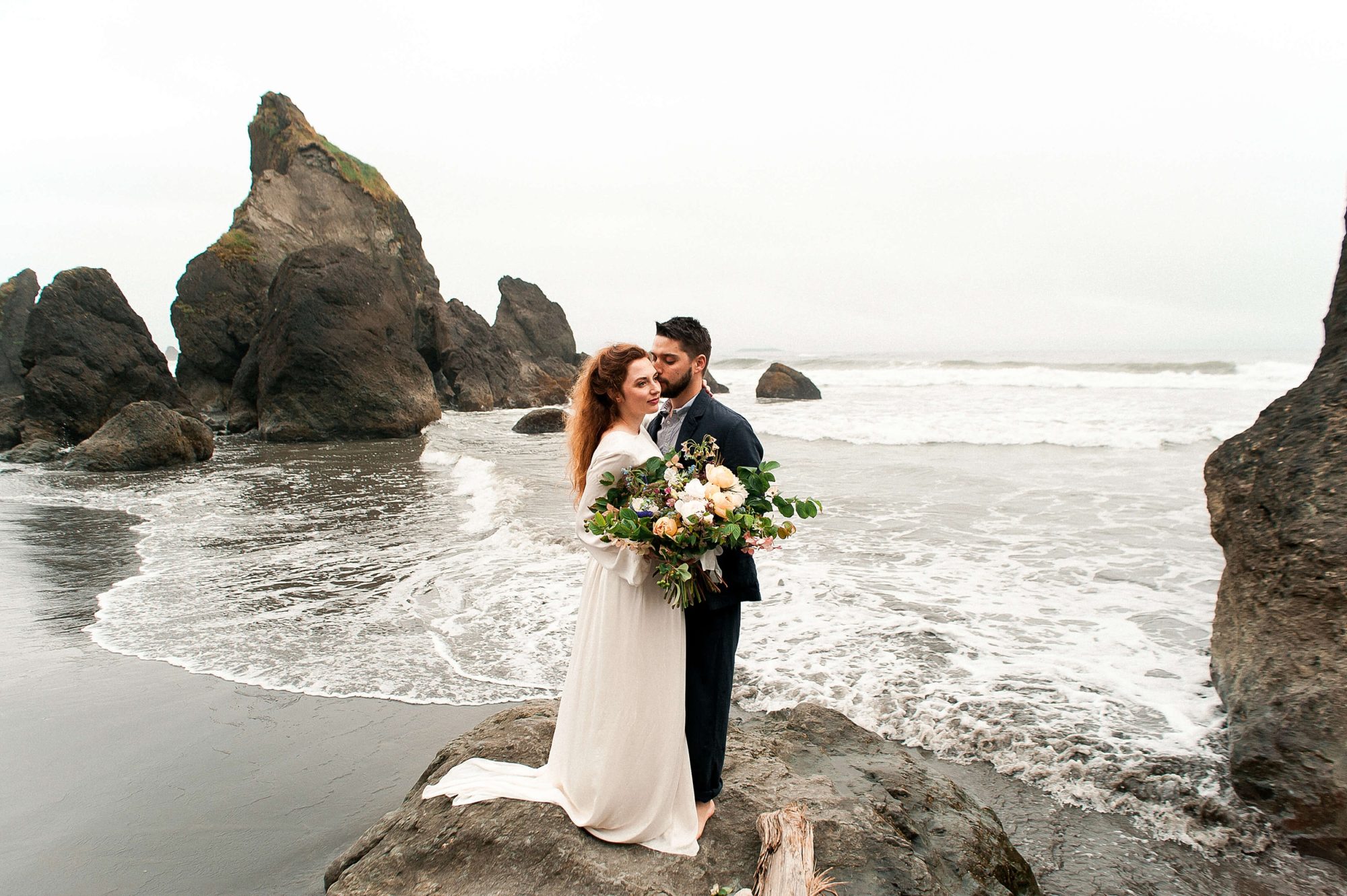 bride and groom embracing on a rock on the beach at their at their Seabrook wedding
