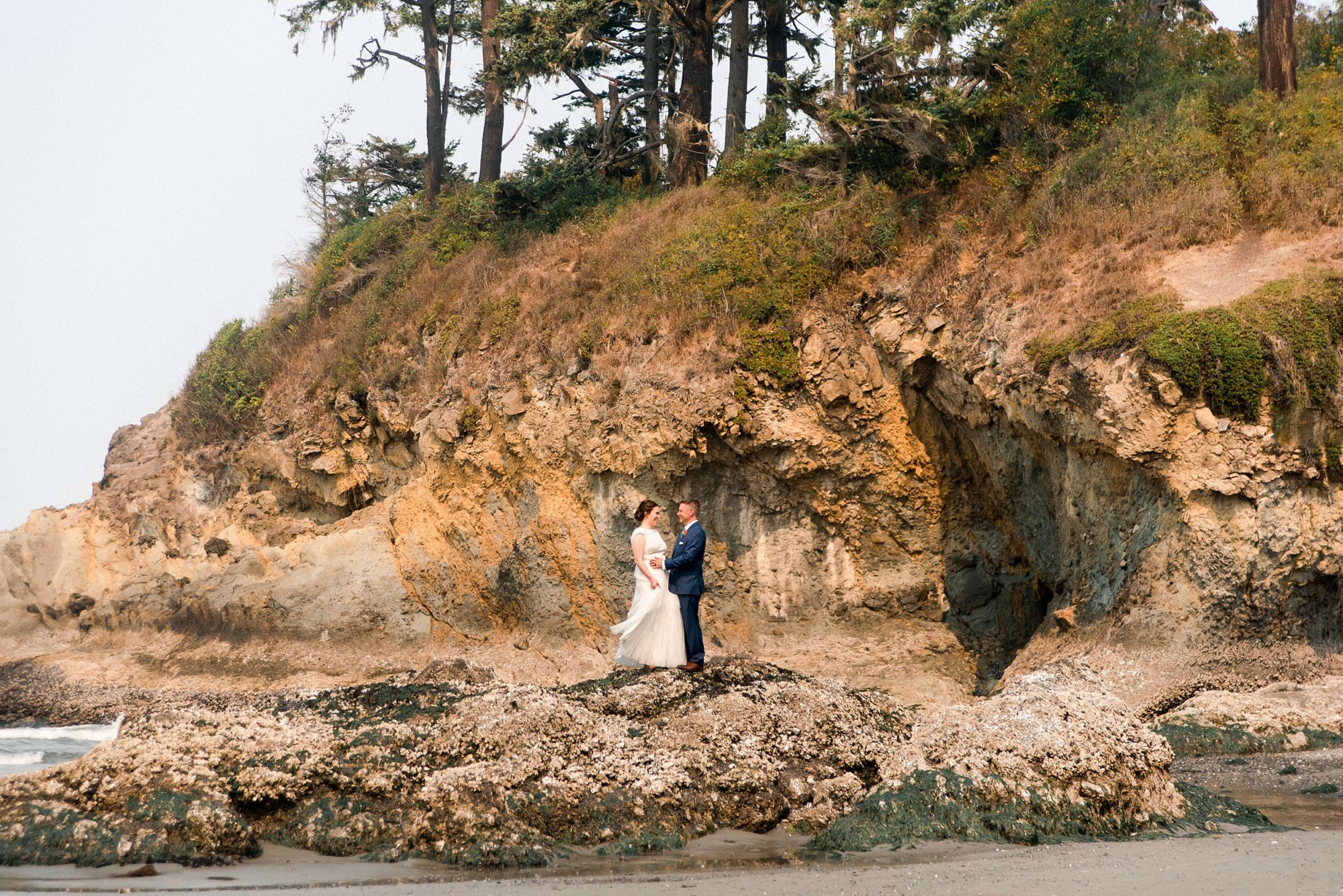 bride and groom standing on a large rock formation at their Seabrook wedding