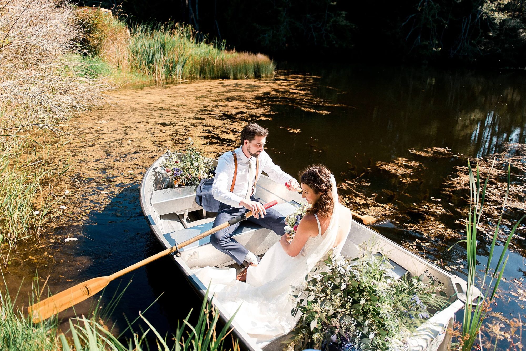 bride and groom in a row boat on a lake at their Lakedale Resort Wedding