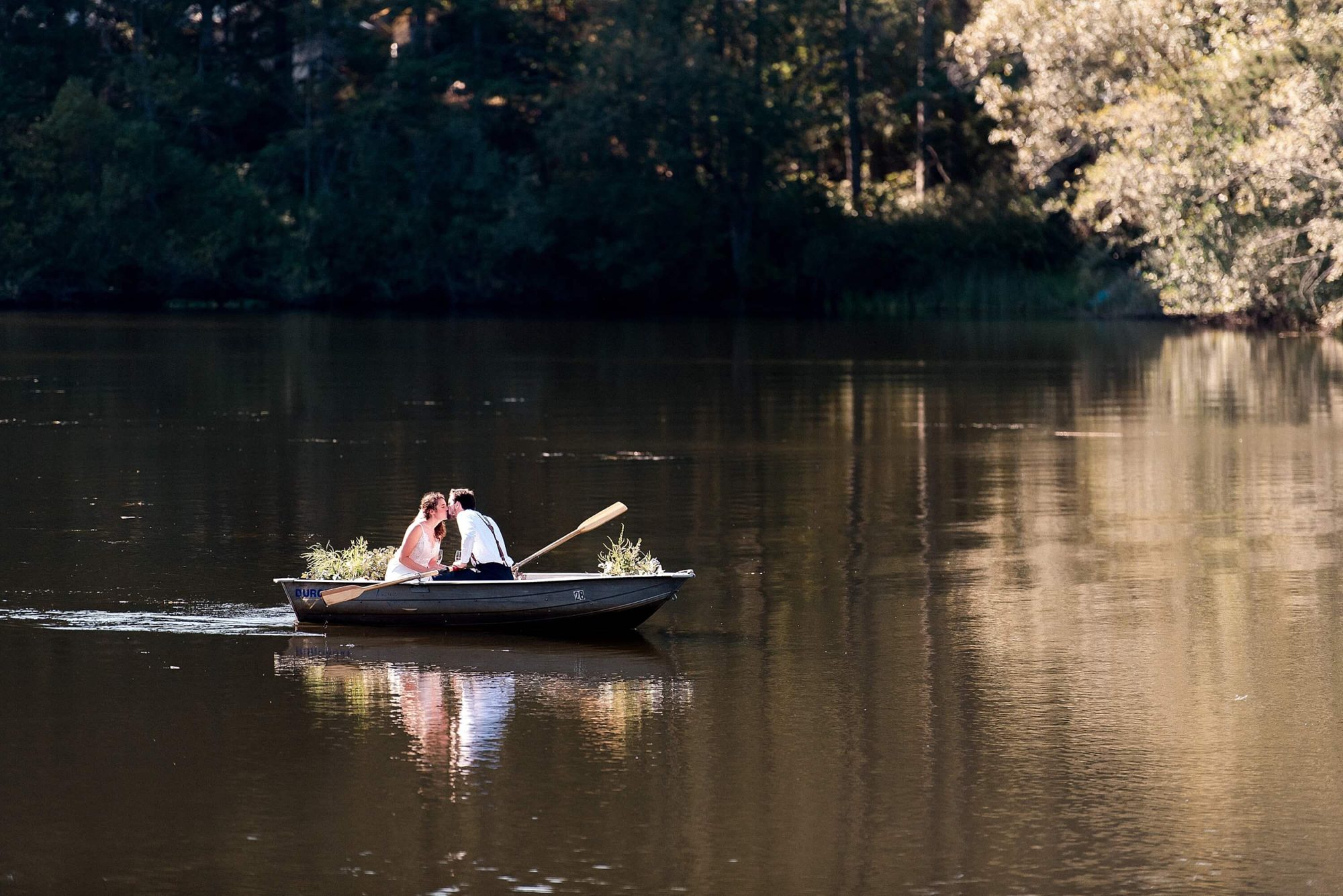 bride and groom sharing a kiss on a rowboat at their Lakedale Resort Wedding