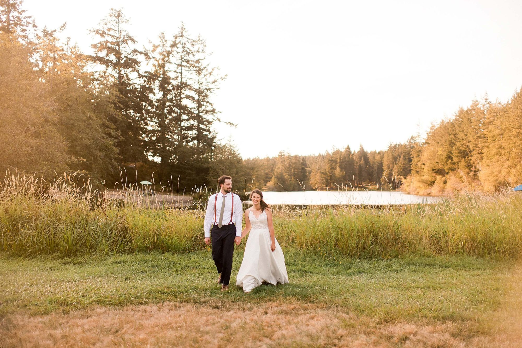 bride and groom walking hand in hand through a field at their Lakedale Resort Wedding