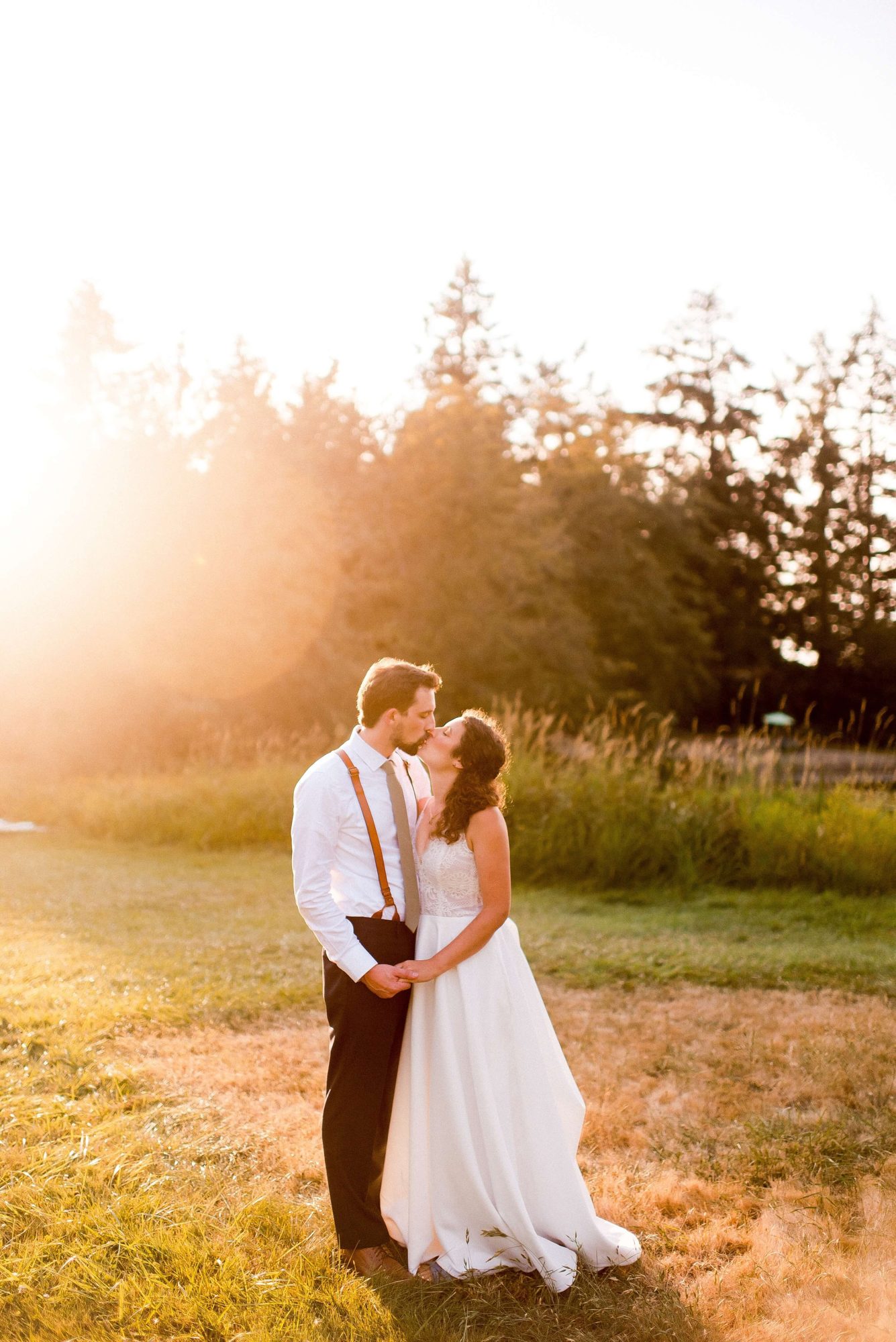 bride and groom sharing a kiss at sunset in a field at their Lakedale Resort Wedding