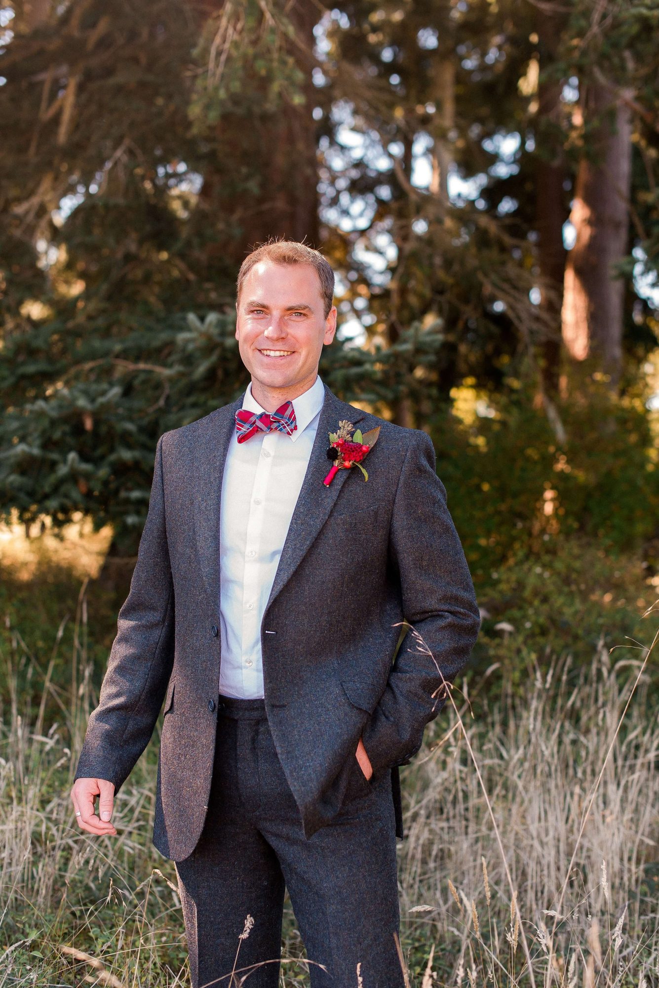 groom in grey suit and red bowtie smiling at their Whidbey Island Wedding