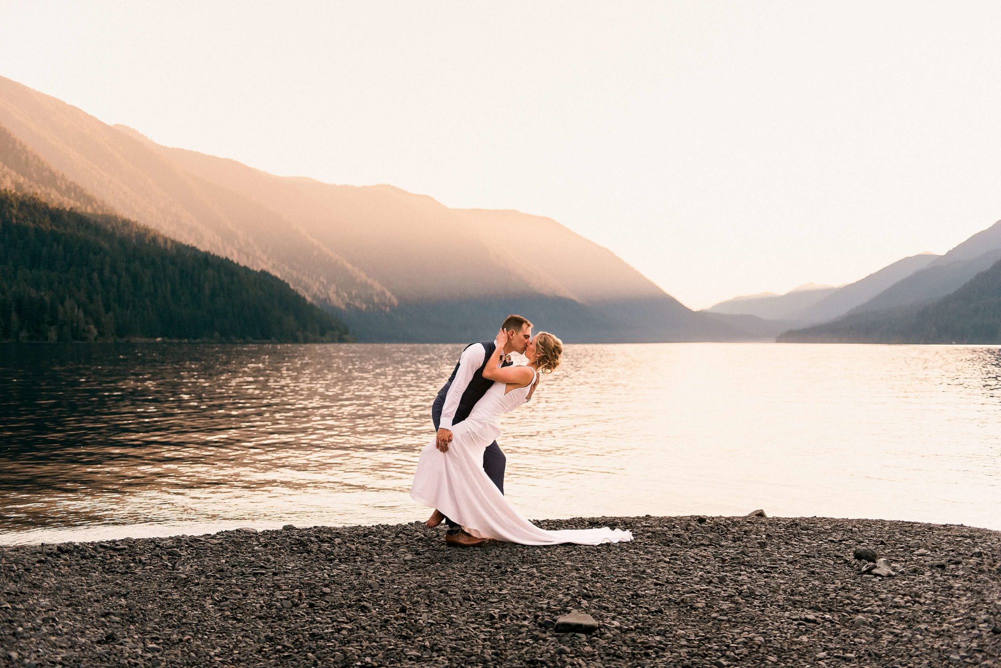 Bride and groom kissing on the beach at sunset at Lake Crescent