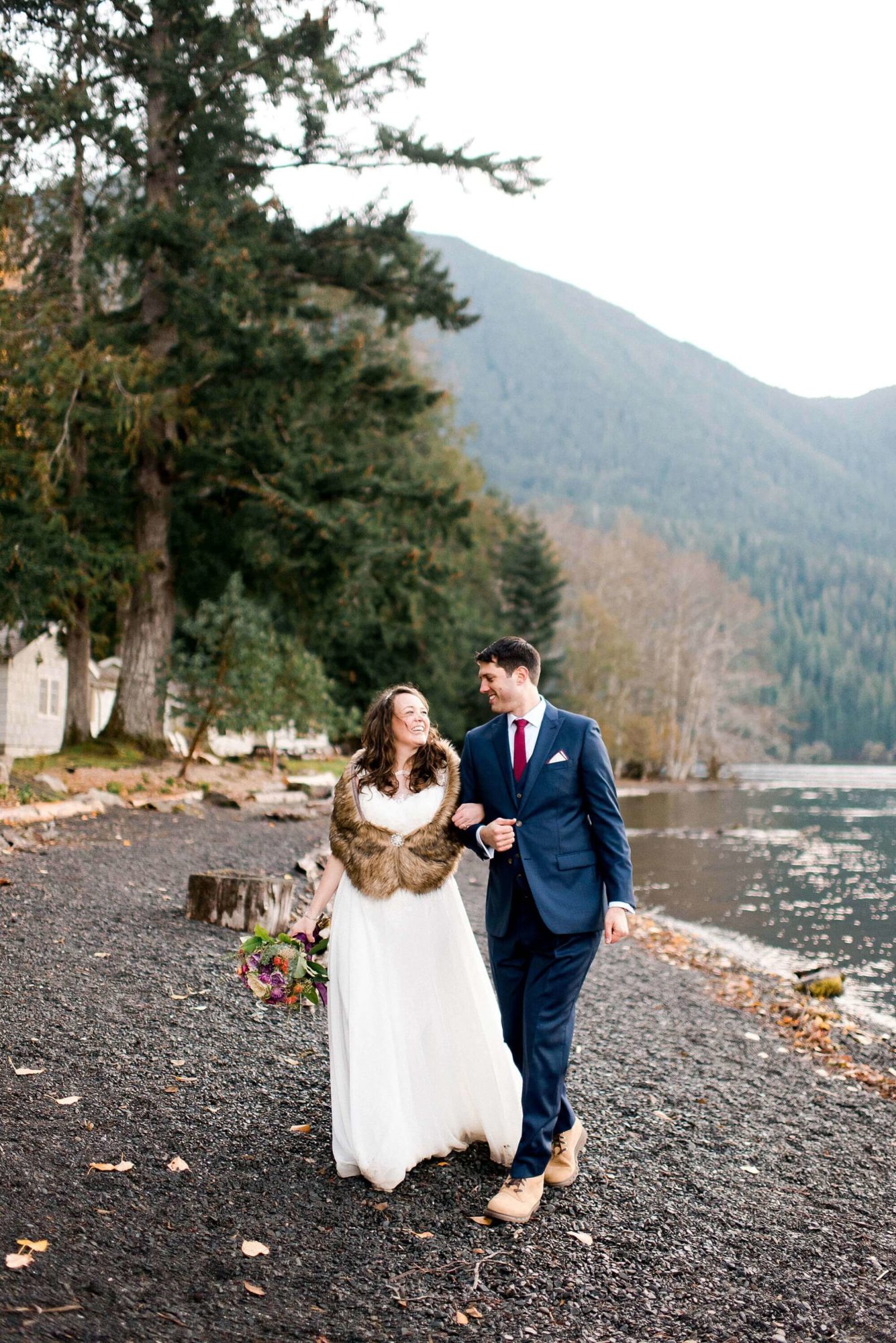 Bride and groom walking on the beach at Lake Crescent Lodge in Olympic National Park