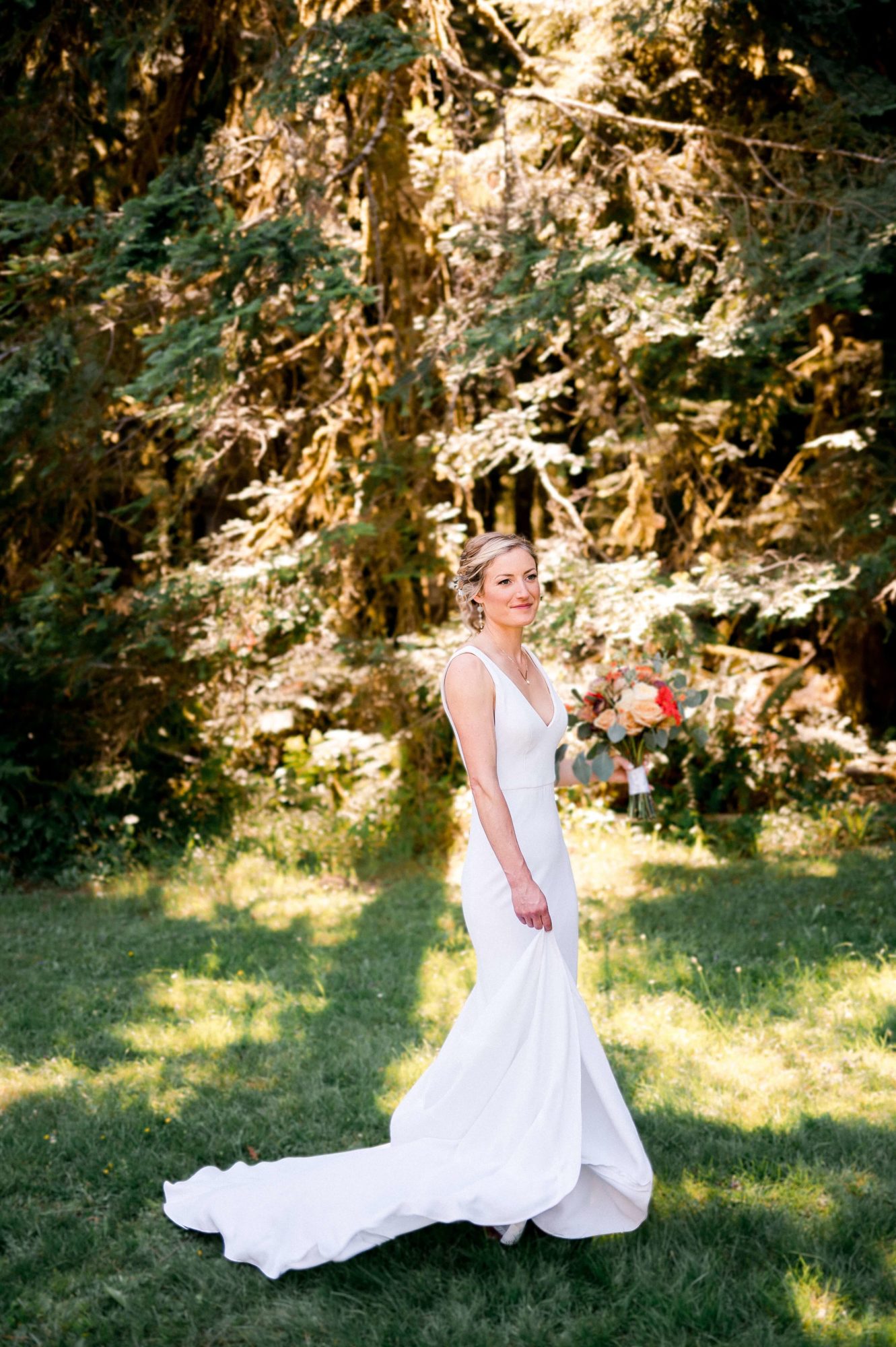 a bride at The Lodge at St. Edwards holding flowers and walking through the forest