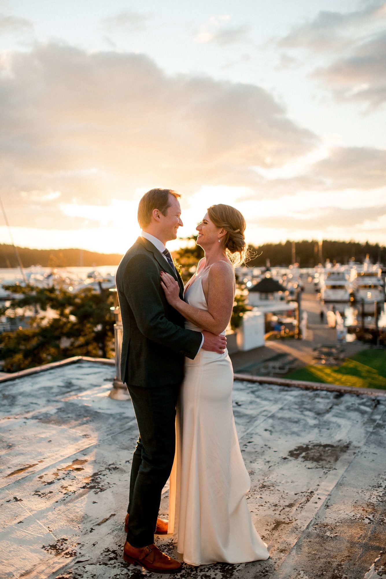 bride and groom standing on a roof overlooking the Roche Harbor Wedding venue at sunset