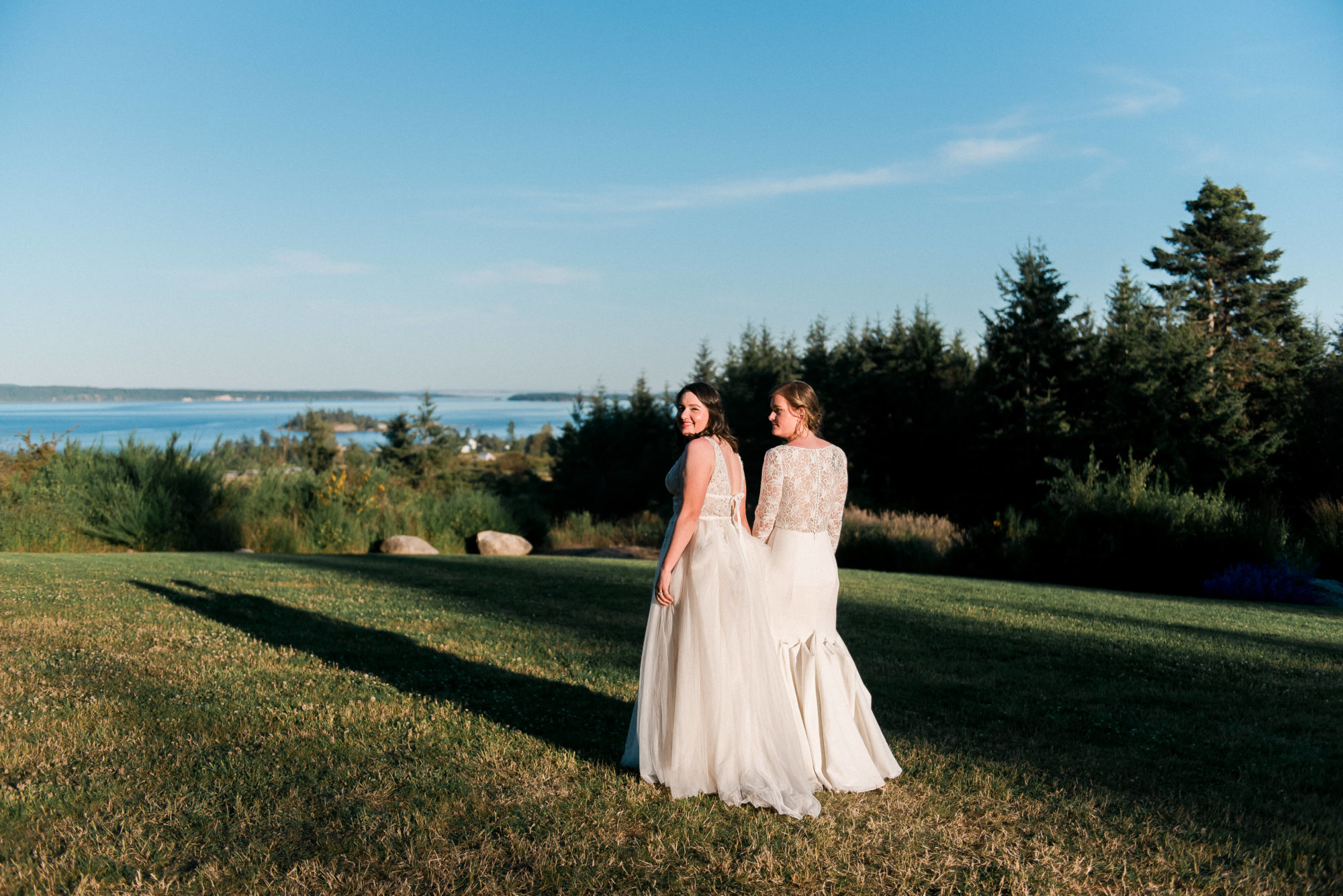 brides holding hands in a field during their Saltwater Farm Wedding
