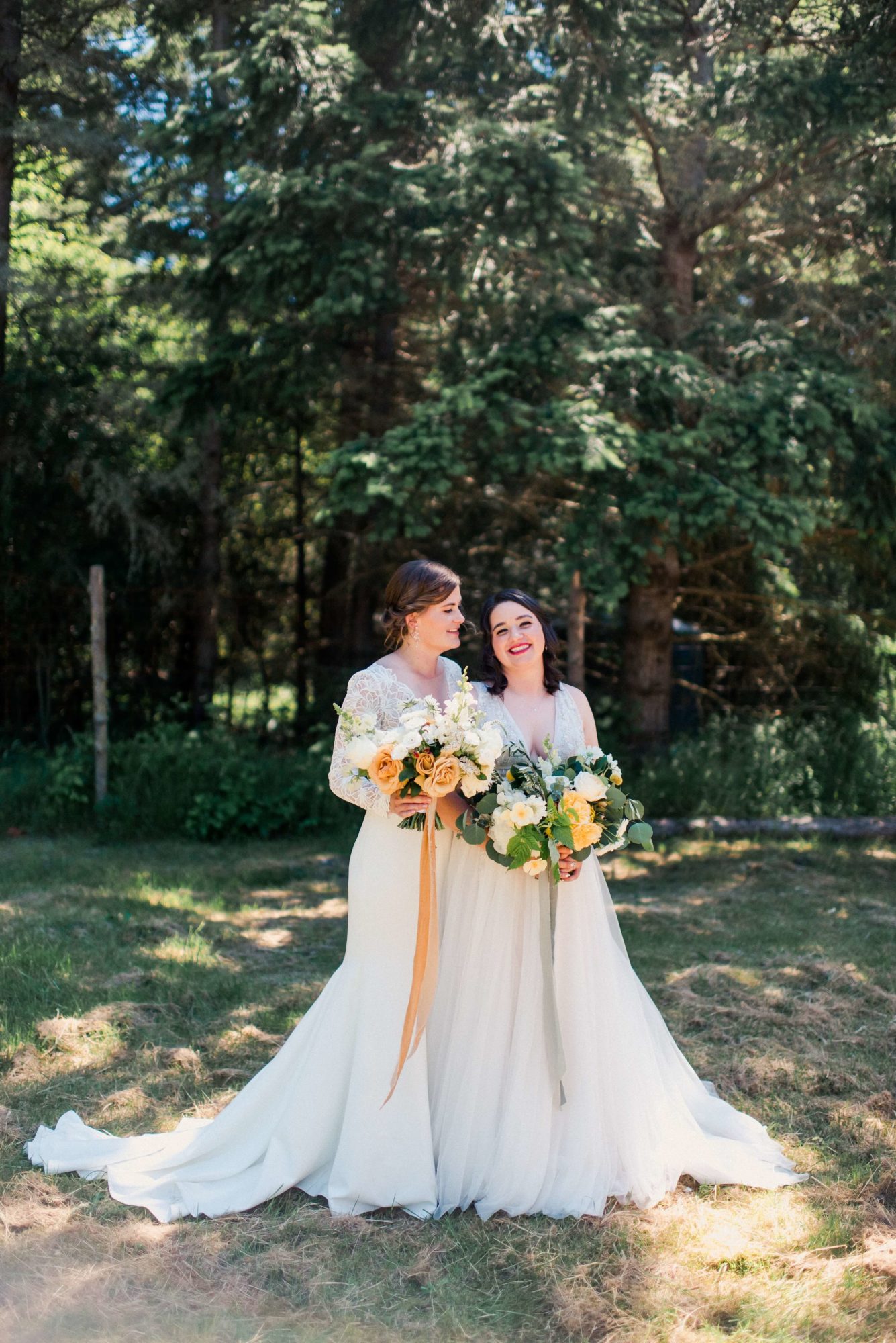 brides laughing in front of a row of trees at Saltwater Farm Wedding