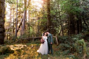 bride and groom with foreheads touching with the sun shining through the trees at Islandwood wedding venue