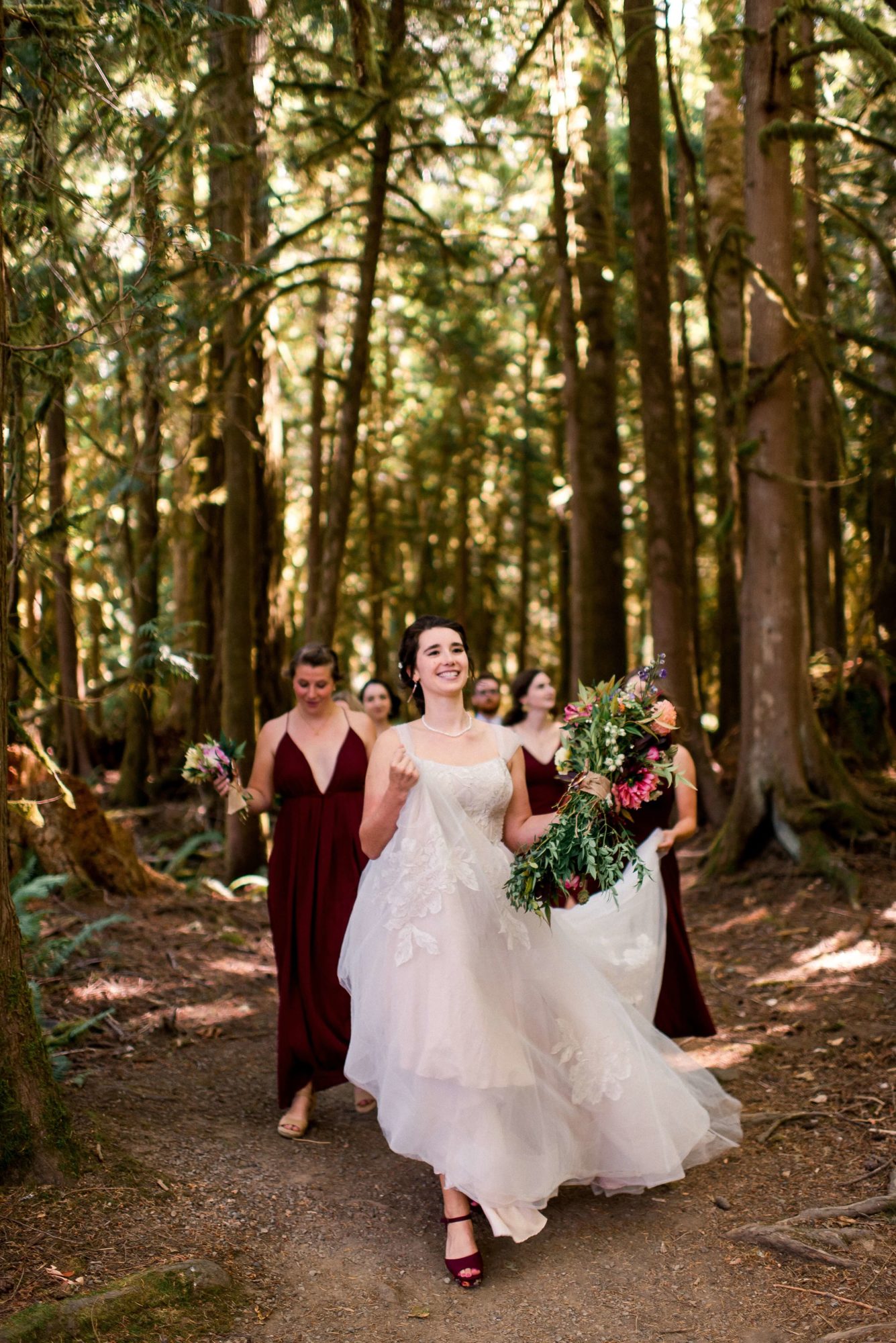 bride walking with her bridesmaids through the forest at Islandwood wedding venue