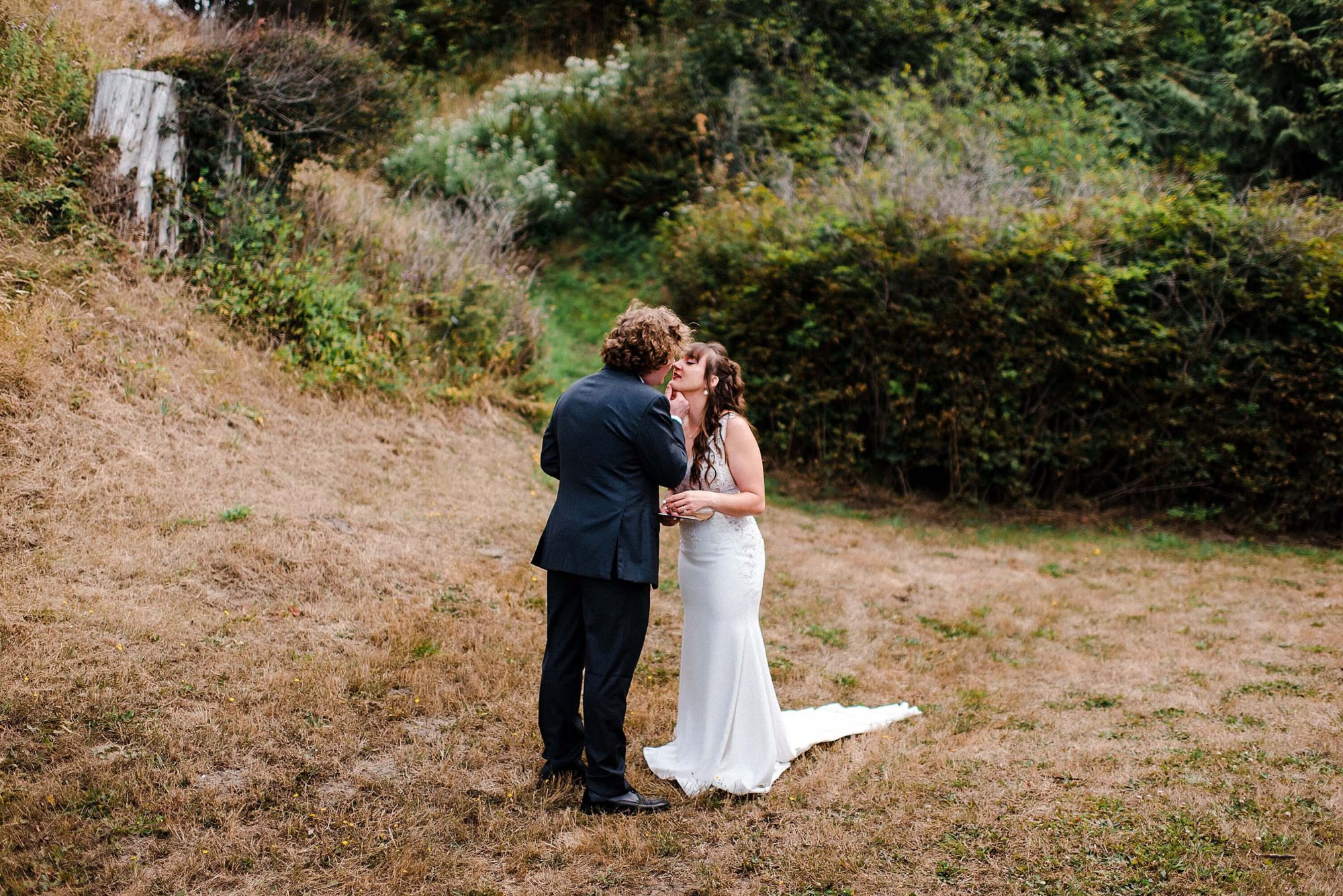 groom holding his bride's chin in a field at their Whidbey Island Wedding